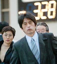 Pedestrians pass an electronic board flashing a fall in share prices in Tokyo