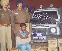 Ajay Kumar, nabbed for trying to smuggle liquor in a suspected Uttaranchal Government Gypsy, is seen with the contraband 