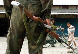 A soldier stands guard as commuters walk past near the border with Bhutan