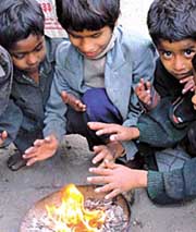 Cold comfort: Children huddle around a fire as cold winds sweep the Capital on Thursday