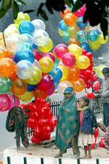 Street children stand next to balloons on the eve of New Year in New Delhi.