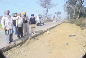 The sarpanch of Ottalan village points towards the damaged stretch of the Samrala-Khanna road