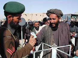 A Pakistani security guard checks the identities of Afghan nationals entering Pakistan at Chaman border