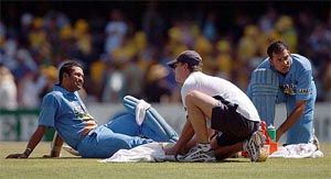 Sachin Tendulkar has his leg checked by the team doctor as V.V.S. Laxman ties his shoelace