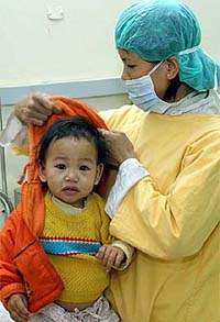 A woman dresses her child, who's suspected of having bird flu, at Vietnam's National Hospital of Pediatrics in Hanoi 