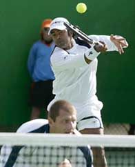 Leander Paes plays a shot as his partner Tomas Cibulec of the Czech Republic watches during their first round match
