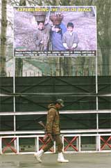 A soldier walks under a billboard with peace message in Srinagar 