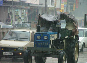 Commuters on a tractor try to shield themselves from heavy downpour which lashed Bathinda 