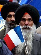 Sikhs wave French national flags as about 3,000 Sikhs from across Europe march on a Paris boulevard to defend their traditional headgear against a looming French ban on religious symbols in state schools