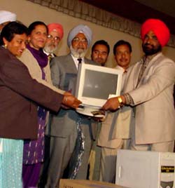 Mr Jagpal Singh Khangura hands over a computer to a local resident at Mandi Ahmedgarh, near Ludhiana, on Thursday.