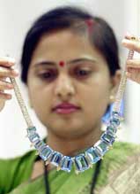 A sales woman shows an unique piece of blue topaz necklace to customers at a jewellery exhibition in Kolkata 