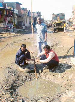 MC workers clear a blocked manhole at Hargobind Nagar in Ludhiana