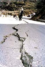 A man walks by cracks in the road caused by an earthquake