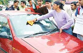 Activists of the Youth Congress clean the windscreen of a car to protest against rise in unemployment 