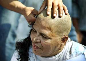 Christian woman Anna Pereira, aged 65, gets her head shaved during a protest rally in Mumbai