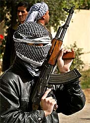 A masked Sunni militiaman stands guard during the funeral of Dhamir Suleyman al-Dhari, a Sunni cleric, in Baghdad 