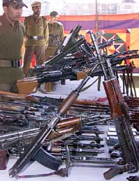 Policemen stand beside seized rifles in a camp in Kupwara, North of Srinagar, on Monday.