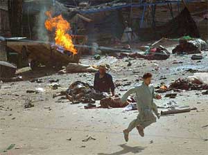 Moments after the attacks, a youth runs past the victims and burning debris