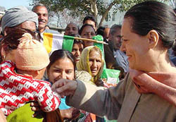 Congress President Sonia Gandhi tries to shake hands with a child during her Road Show at Kanaid village, near Sundernagar, in Himachal Pradesh on Thursday. 