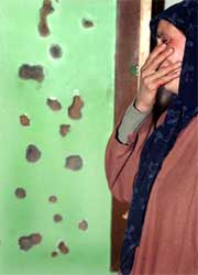 A Kashmiri Muslim woman weeps next to a bullet-riddled wall after a gunbattle between security forces and militants in Kanpora village, 27 km west of Srinagar