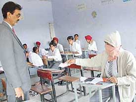 An official of the Punjab School Education Board keeps a safe distance while checking the roll no slip of a student who is suffering from chickenpox at Government Senior Secondary School