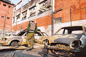 A BSF jawan walks past the debris of the building which was attacked by militants in Srinagar on Tuesday.