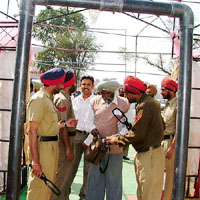 Policemen frisk bidders before allowing them to enter the venue of the liquor shops’ auction in Bathinda on Thursday.