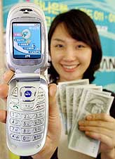 A Hana Bank employee shows new online banking services using mobile phones in Seoul on Monday.