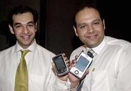 Capital Wireless President Arvind Kapoor (R) and Vice-President Vishal Kapoor pose with the new P300 pocket PC with built-in mobile phone and digital camera at its launch in New Delhi on Wednesday.