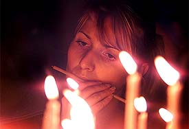 A woman lights candles at St. Marko church during a ceremony marking the fifth anniversary of NATO bombing campaign over Yugoslavia