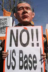 Wearing a mask of President George W. Bush, a South Korean protester holds a banner during a rally against the annual joint military exercises between South Korea and the U.S.
