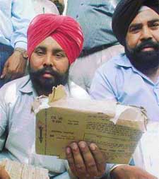 Teachers show torn and improperly sealed packets of question papers at Government Senior Secondary School, Bharat Nagar