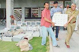Police personnel load a computer seized during a raid at Paradise Solutions in Sector 34