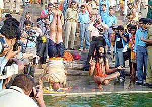 Cameramen photograph sadhus performing yoga on the banks of the historical Kshipra river at Ramghat in Ujjain on Monday.