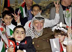 Children pose with Palestinian President Yasser Arafat at his office in the West Bank city of Ramallah on Monday