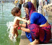 A mother gives her child a holy dip in the Kshipra river during Kumbh mela