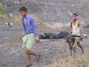 The body of an illegal miner who was killed in a mine accident being carried away