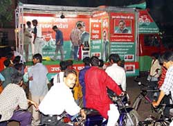 People watch a nukkad natak as part of the Samajwadi Party's election campaign road show for the forthcoming Lok Sabha elections 
