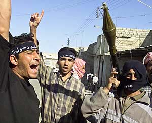 An Iraqi insurgent carries a rocket-propelled grenade launcher in a street after attacking Mosuls city hall