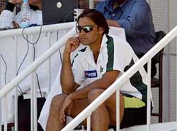 Shoaib Akhtar sits on the stairs of the dressing room to watch the first day of the third Test 