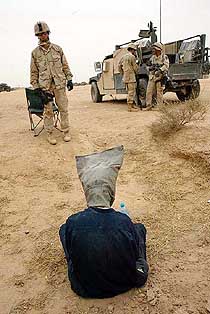 A suspected Muqtada al-Sadr follower is watched over by an American Sergeant