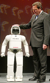 German Chancellor Gerhard Schroeder stands beside humanoid robot 'ASIMO' during the inauguration of Hanover Industrial Trade fair in Hanover