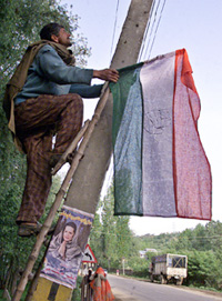 A Kashmiri activist of the Congress climbs a ladder to attach his partys flag to an electric pole in Baramula