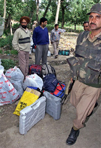 A soldier walks past Kashmiri officials with polling material waiting for transportation in Baramula on Monday. 