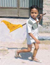 A young boy carries a party flag in a rural area