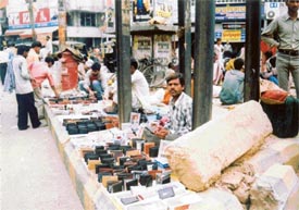 Roadside sellers occupy a median of the road near Ghanta Ghar