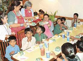 District Governor Kawal Bedi serves food to children of Bal Bhavan at Hot Millions-2. 