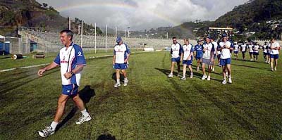 The English cricket team leave the ground after a quick check, as a rainbow looms in the background