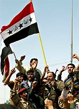 Members of the new Falluja Brigade wave Saddam-era Iraqi flags after they took over security in the western Iraqi city of Falluja