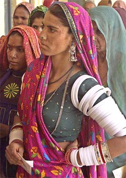 Tribal women awant their turn to cast votes outside a polling booth in Rajasthan